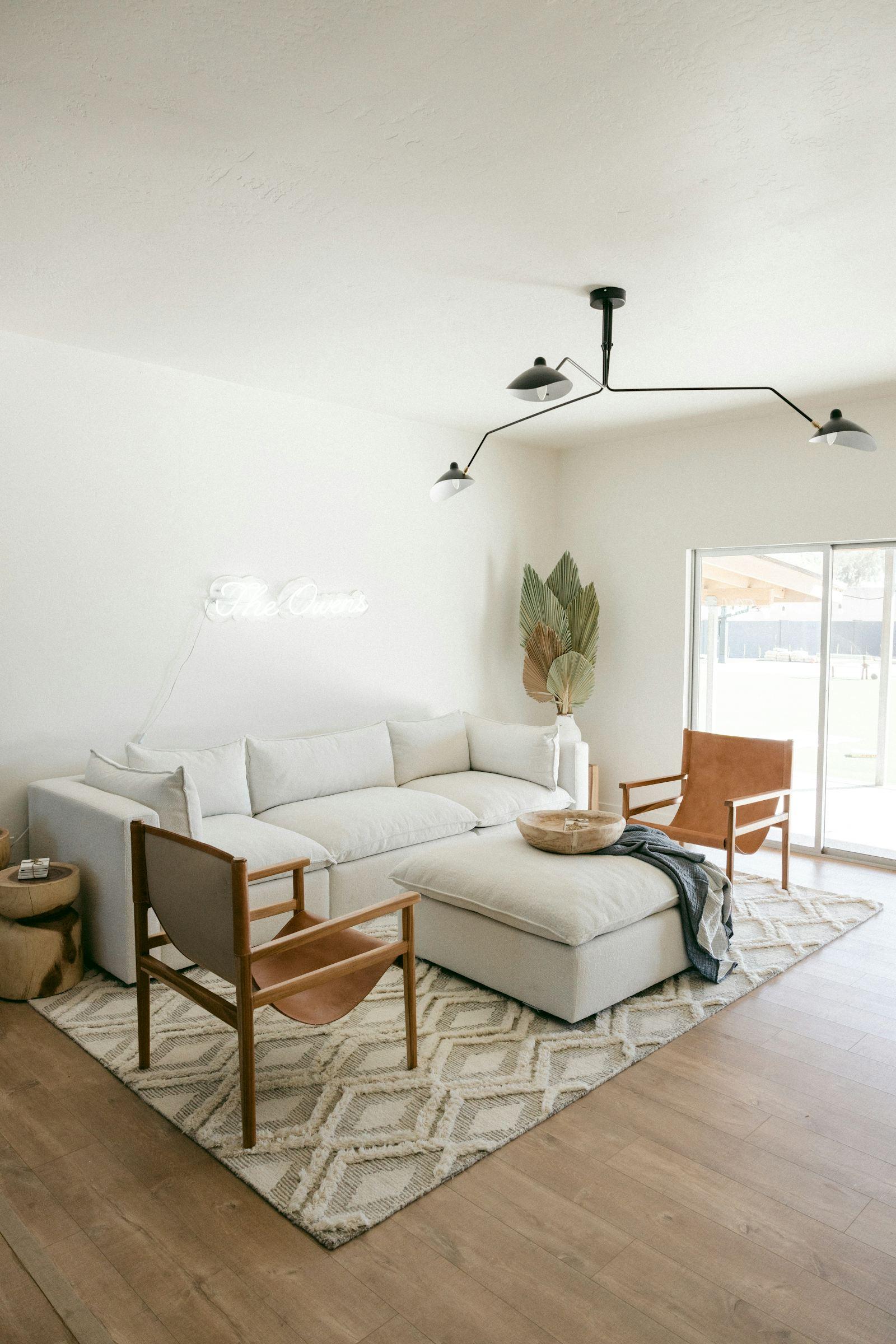 Séjour blanc et lumineux avec canapé gris clair et baie vitrée ouverte, appartement rénové près de Saint-Malo