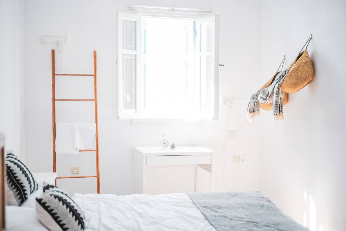 Chambre blanche avec échelle porte-serviettes en bois et fenêtre ouverte, appartement près de Saint-Malo