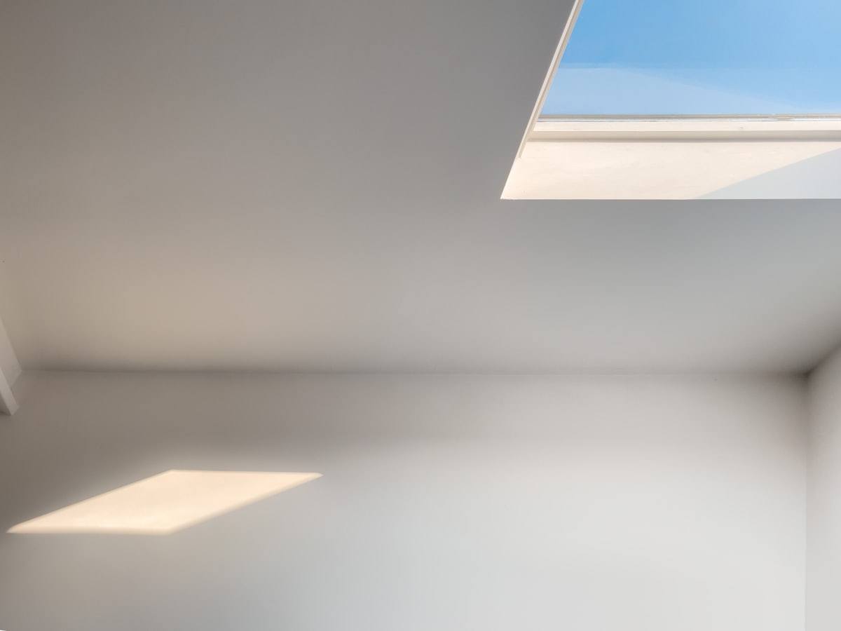 Ouverture zénithale blanche cadrant un pan de mer et de ciel bleu, appartement réaménagé près de Saint-Malo