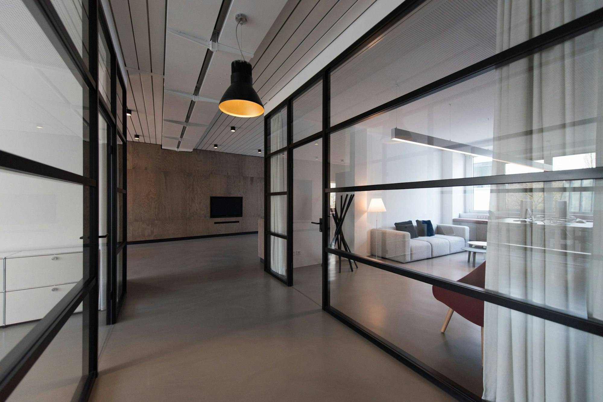 Couloir vitré avec vue sur un salon et une salle de vie, bureaux de Saint-Brieuc