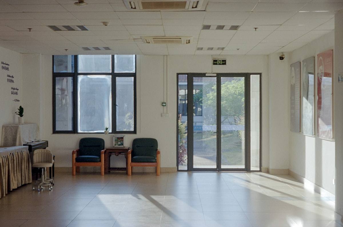 Couloir de circulation vide avec chaises d'attente et grande baie vitrée, cabinet de podologie à Rennes