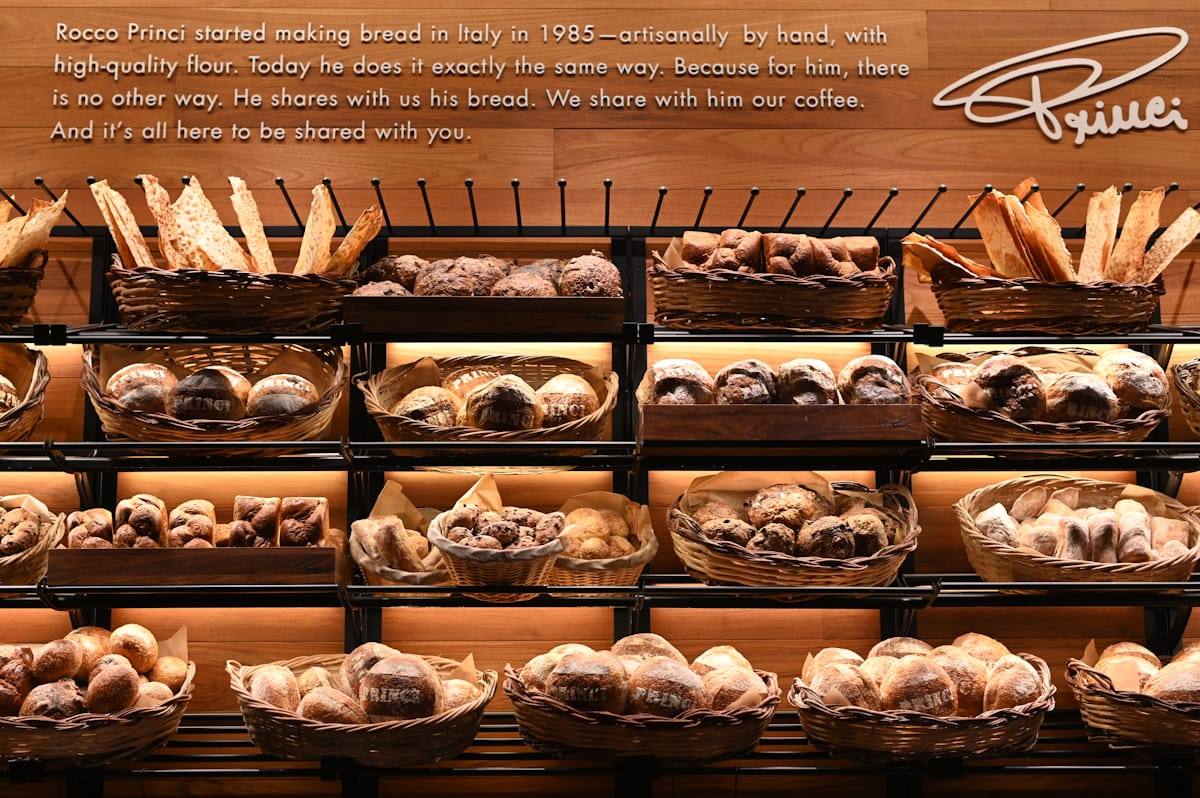 Étagères en bois garnies de pains et de corbeilles de viennoiseries, café-boulangerie vitréen