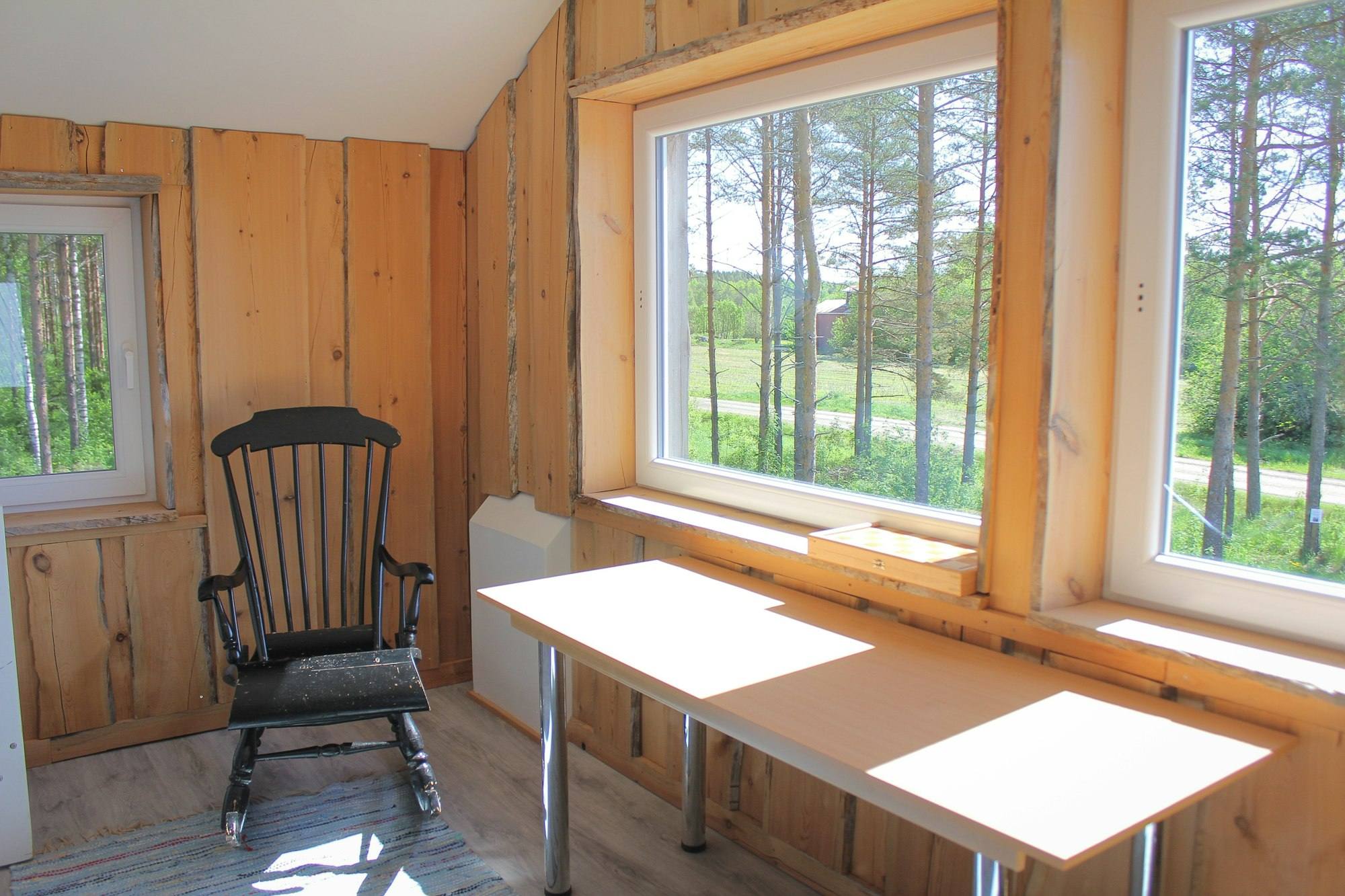 Coin bureau avec chaise à bascule et vue sur la forêt depuis la fenêtre, gîte près de Vitré