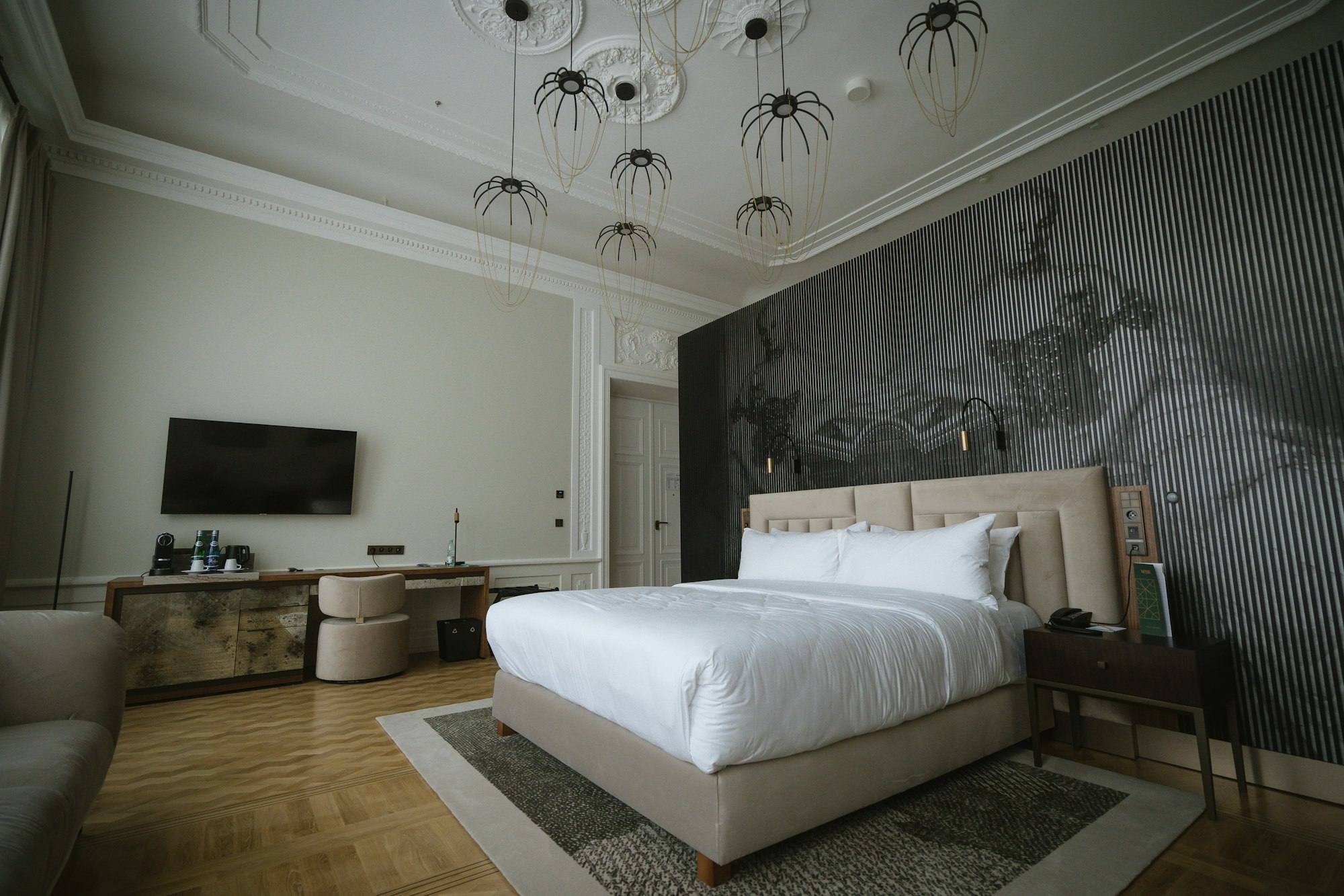 Chambre aux suspensions design et mur rainuré gris, lit beige, hôtel de Saint-Malo