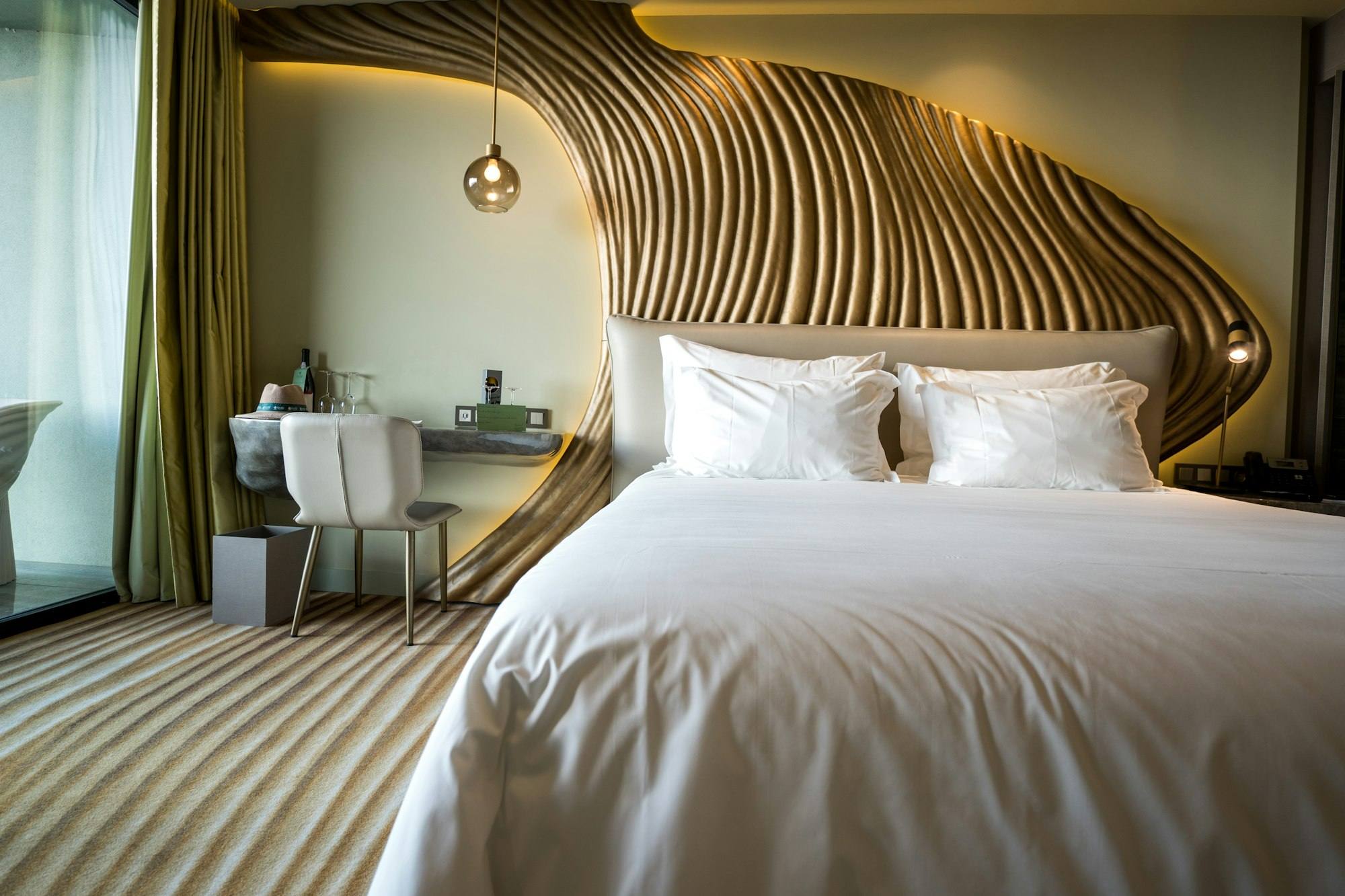 Chambre avec tête de lit sculptée dorée ondulée et coin bureau, hôtel de Saint-Malo