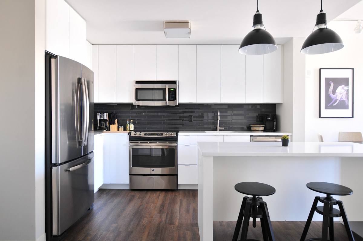 Cuisine blanche avec îlot central, tabourets noirs et parquet en chêne, loft réagencé à Rennes
