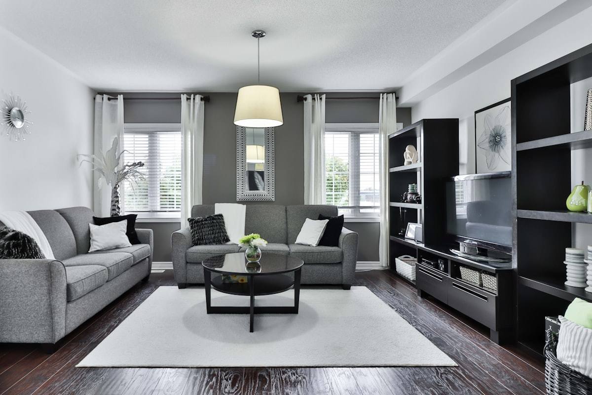 Salon avec canapé gris, meuble télévision noir et tapis clair, loft réagencé à Rennes