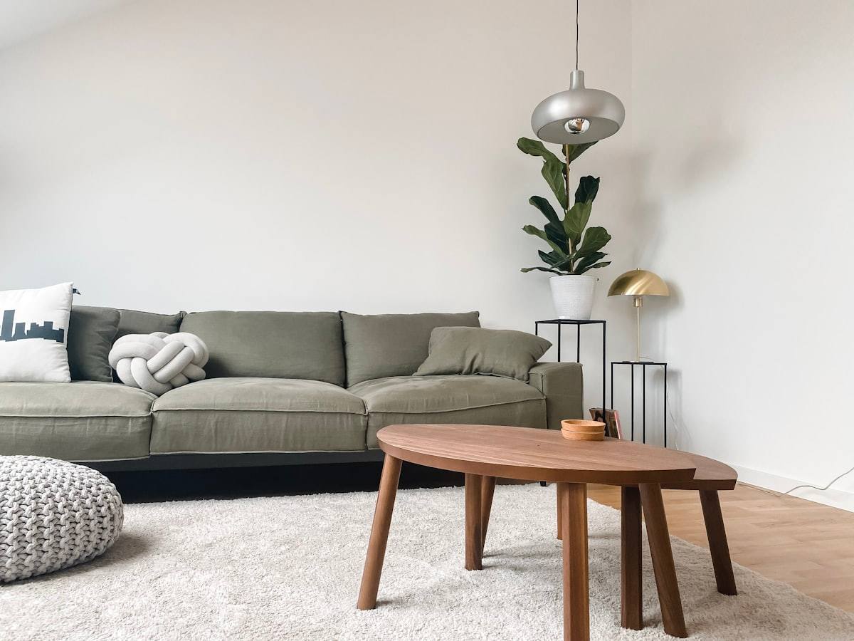 Coin salon avec canapé vert olive, table basse ronde en bois et suspension métallique, loft à Rennes