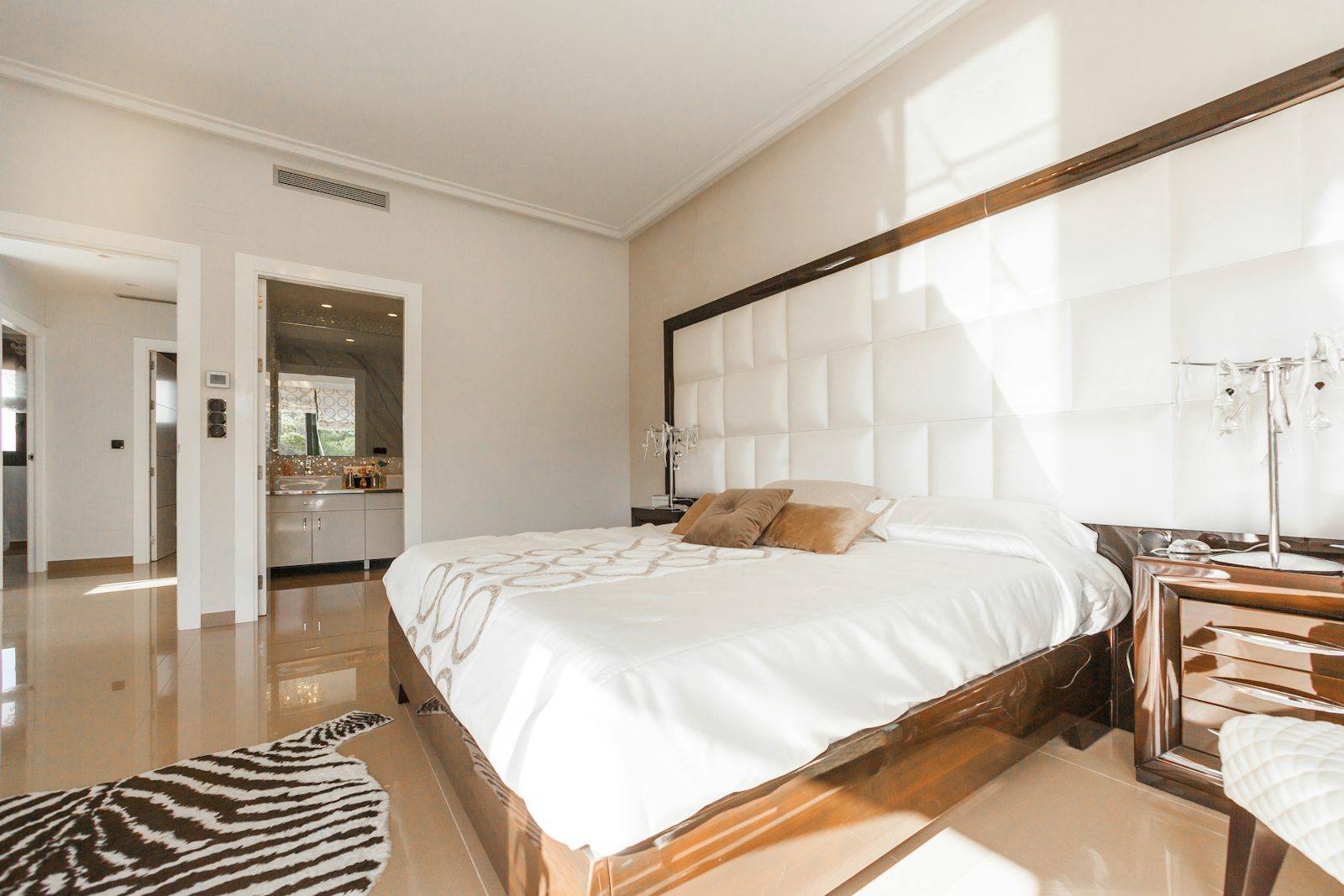 Chambre avec tête de lit capitonnée blanche et tapis zébré, loft rennais réagencé