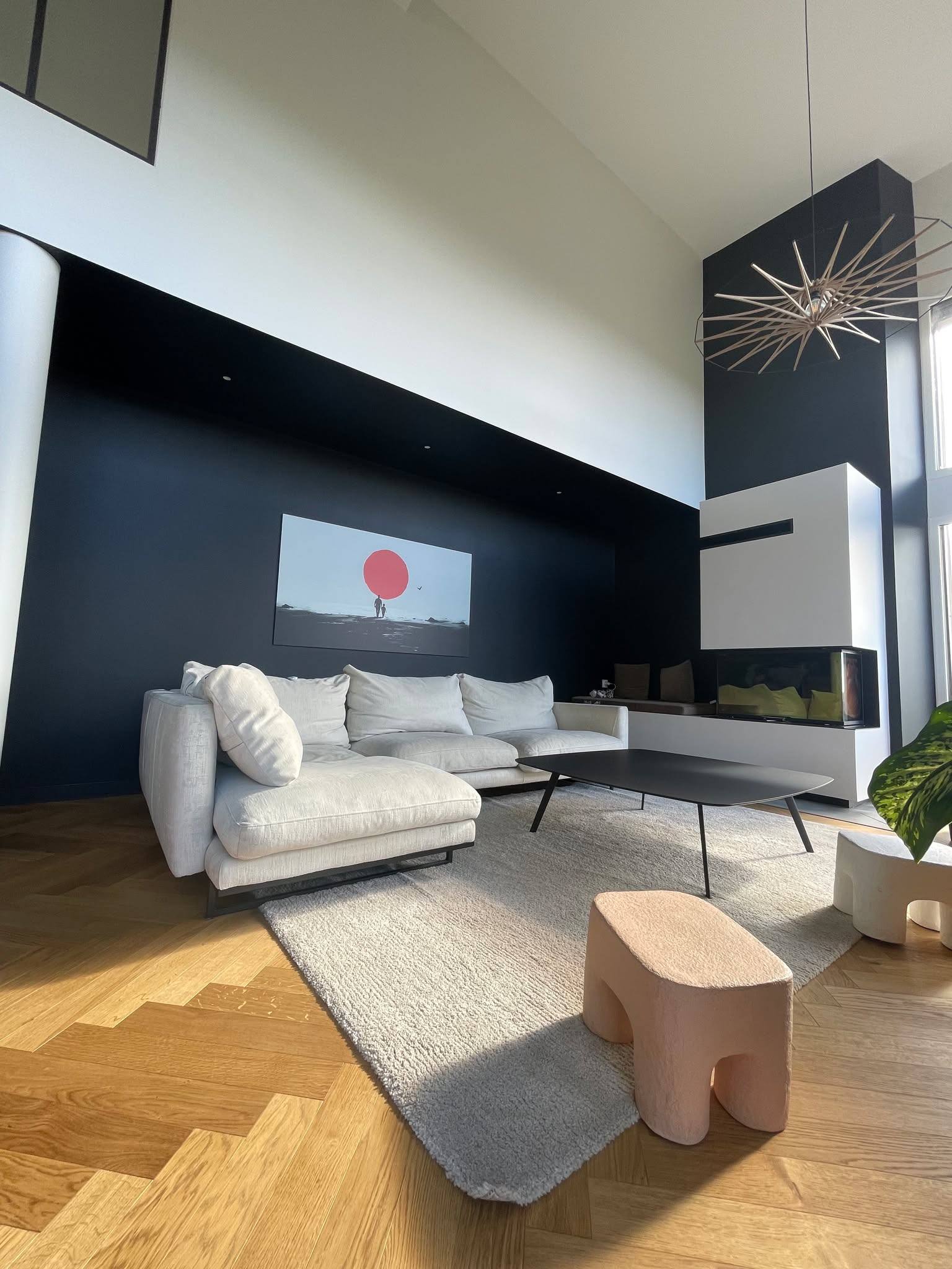 Canapé blanc le long d'un mur bleu nuit sous un plafond de grande hauteur, suspension en bois tressé en premier plan