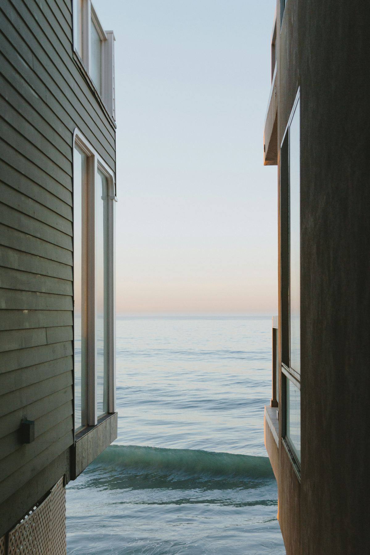 Fenêtre ouverte sur une vague et un bardage en bois gris, villa rénovée en bord de mer à Dinard